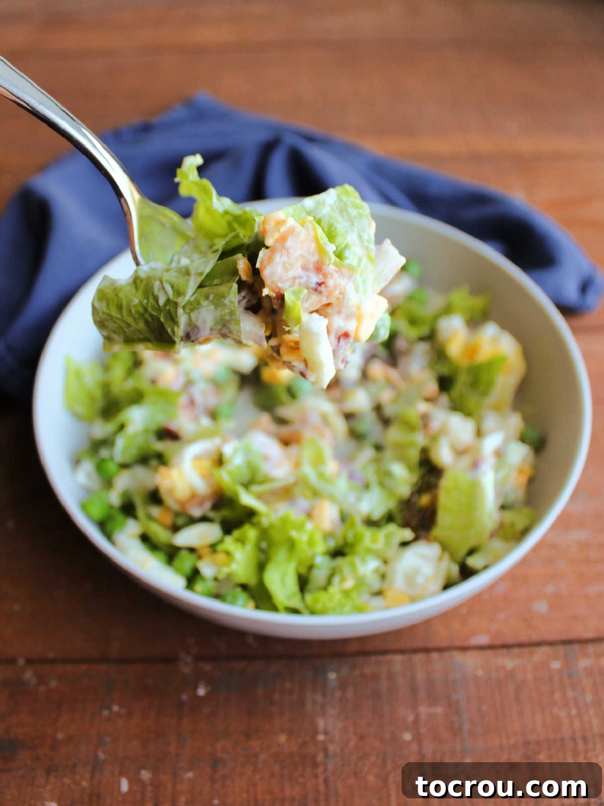 Bite of seven layer salad on fork, ready to eat. 