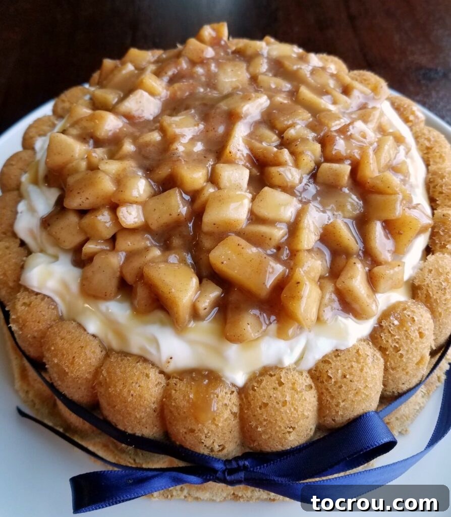 A close-up shot revealing the rich cinnamon sponge cake generously filled with a creamy, fluffy cream cheese filling and lavishly topped with tender caramel apples, ready to be served.
