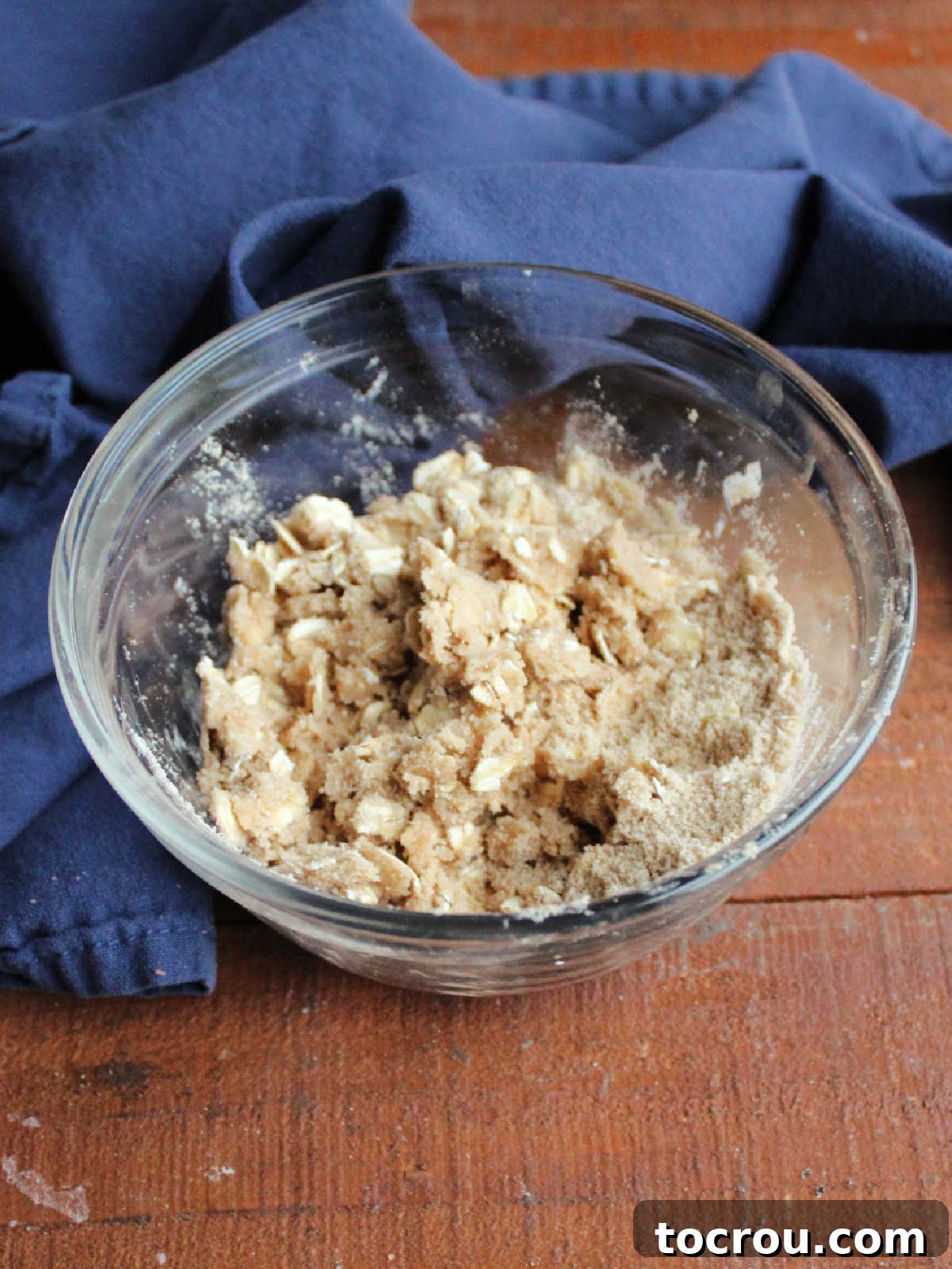 Small mixing bowl with buttery oat and brown sugar mixture ready to go on the pie.