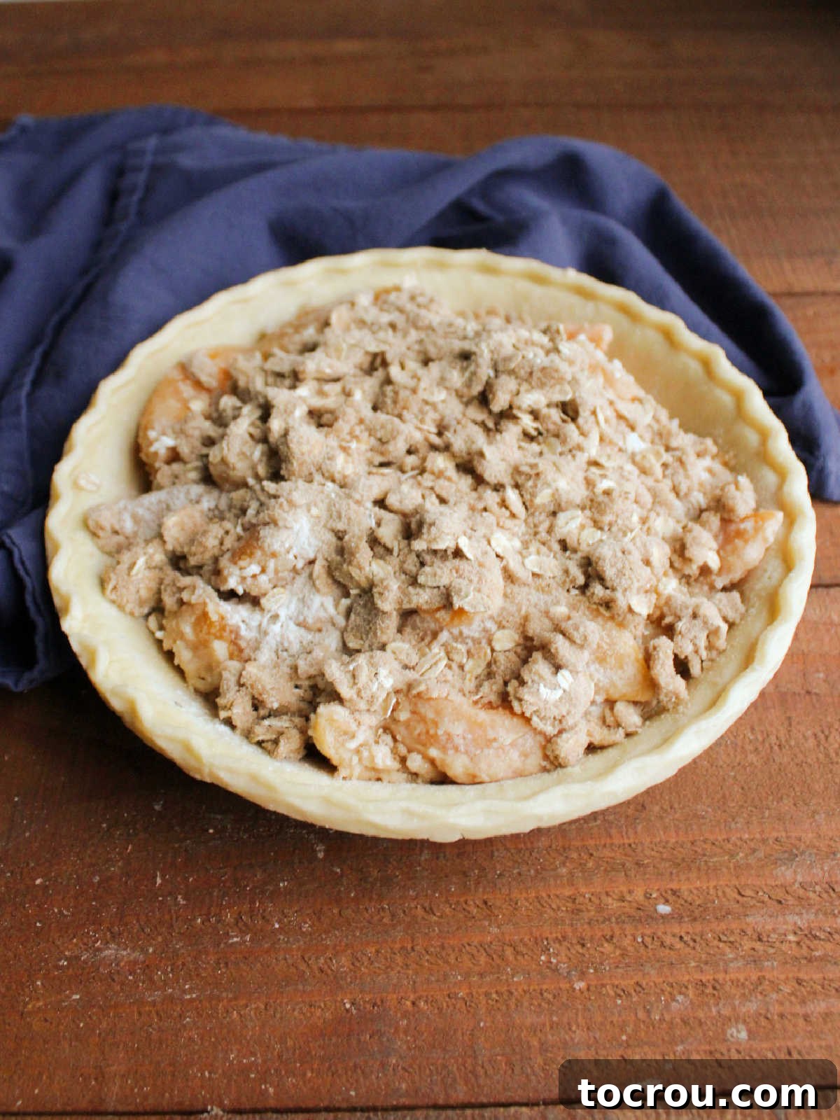 Pie filled with peaches topped with brown sugar and oat crumb topping.