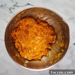 Mashed sweet potatoes with butter speckles in mixing bowl, getting ready to be made into pie filling.