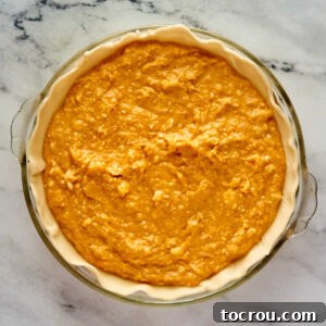 Sweet potato pie filling in pie crust, ready to go in the oven.