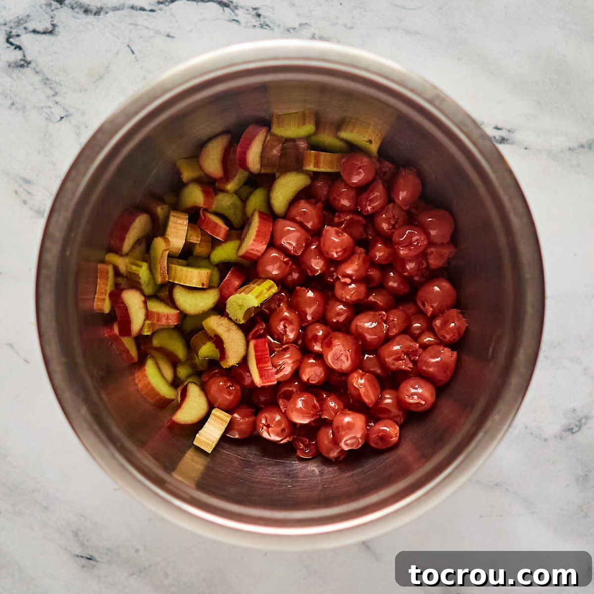 Sweet and Tart Cherry Rhubarb Pie 5 Mixing bowl with cherries and sliced rhubarb inside, ready to be made into pie filling.