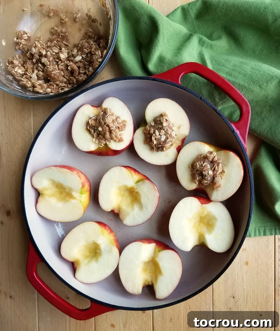 apples halved and cored getting filled with crisp mixture in enameled cast iron braiser.