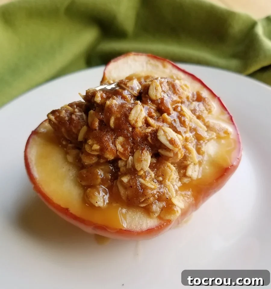close up of an apple half transformed into a mini apple crisp baked apple with a drizzle of caramel sauce.