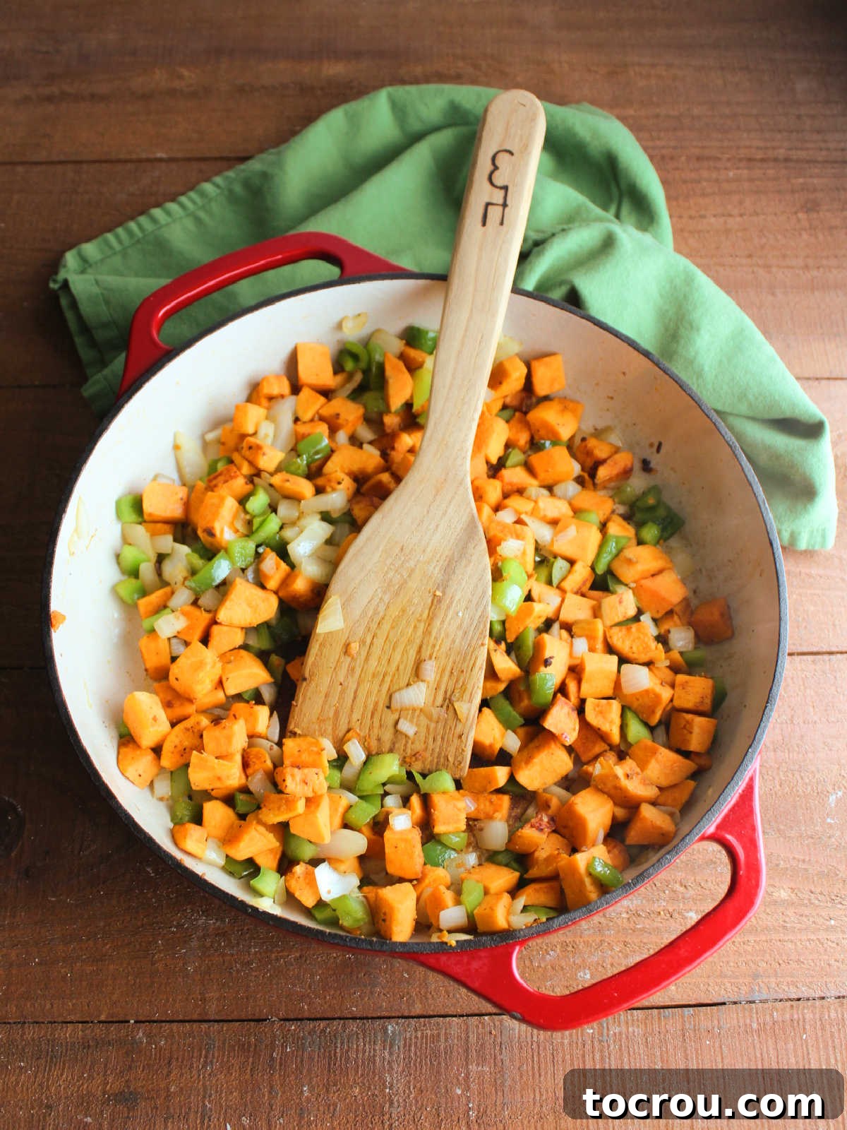A close-up of a skillet filled with evenly cooked sweet potato cubes, mixed with diced onions and green bell peppers, glistening slightly from the cooking process, ready for the chorizo to be returned.