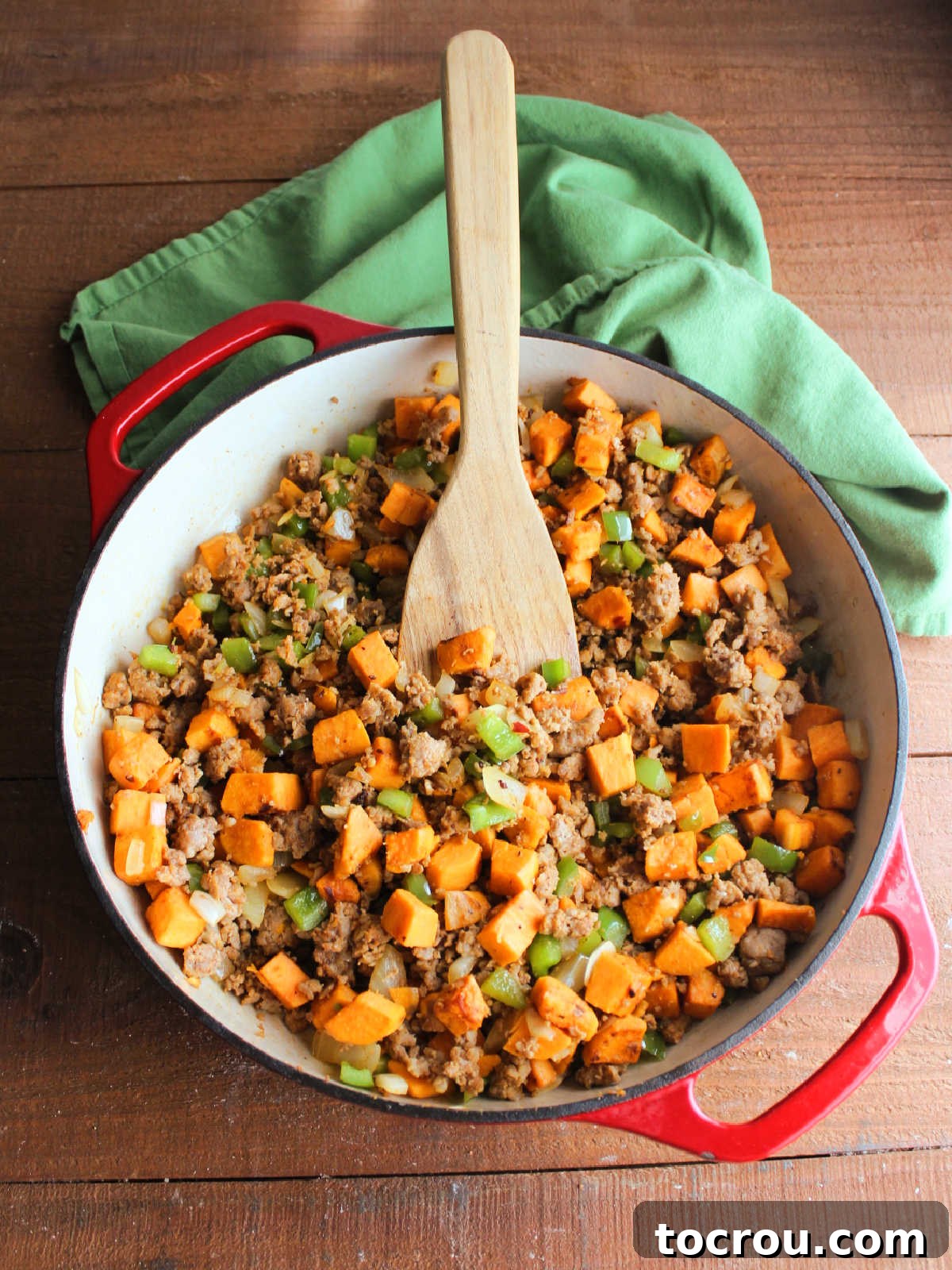 A large skillet brimming with the fully prepared sweet potato chorizo hash, featuring golden-brown sweet potatoes, vibrant green peppers, and tender onions, all ready to be dished out and enjoyed.