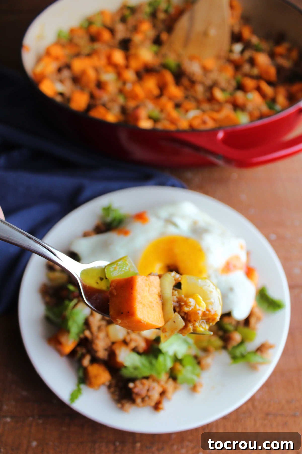 A close-up of a fork holding a perfect bite of sweet potato hash, showcasing a mix of tender sweet potato, savory chorizo, and crisp green bell peppers, ready to be enjoyed.