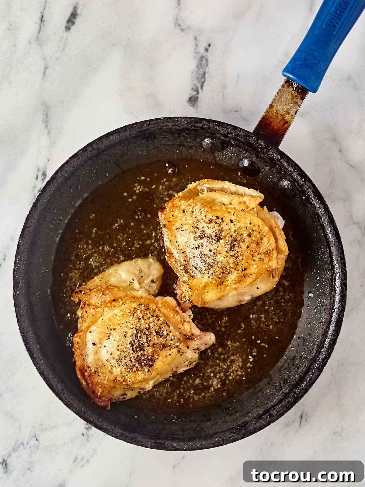 Browned chicken thighs in skillet.