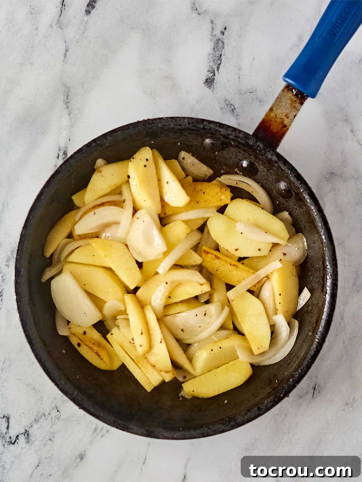 Sliced apples and onions cooking in the same skillet the chicken thighs were cooked in.