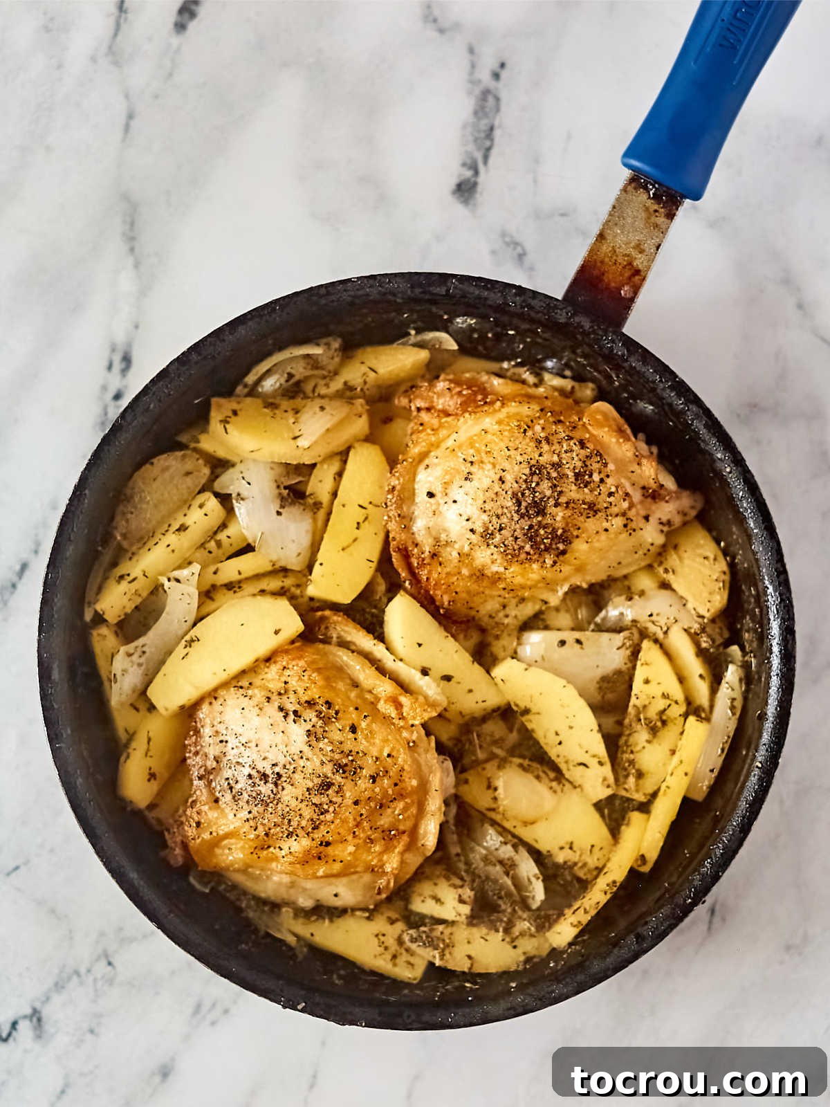 Skillet with chicken thighs added back in with the cooked apples and onions.