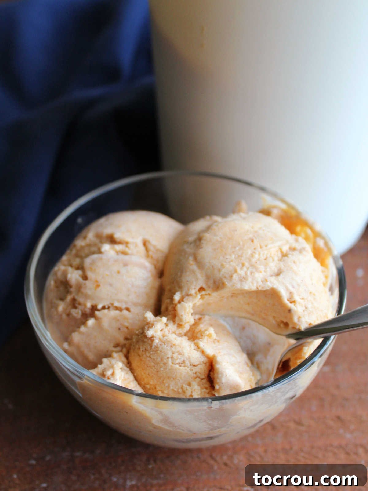 Velvet Pumpkin Ice Cream 7 Spoon getting a bite of pumpkin ice cream from a scoop in a small bowl.