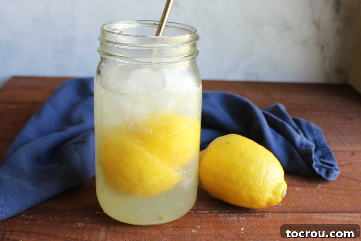 Tangy Shaken Lemonade 2 Glass jar with homemade lemonade shake up with bits of lemon and plenty of ice, ready to drink.