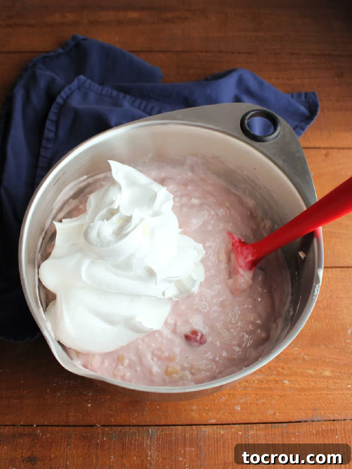 Folding Cool Whip into cherry, pineapple, and cream cheese mixture. 