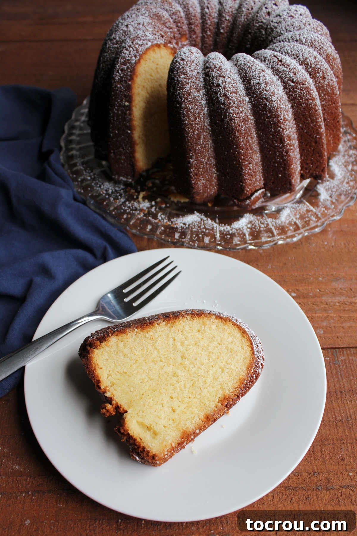 Slice of condensed milk pound cake on plate with fork, ready to eat.