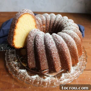 Bundt shaped sweetened condensed milk pound cake dusted with powdered sugar with one piece being lifted out showing dark golden brown crust and cream colored interior.