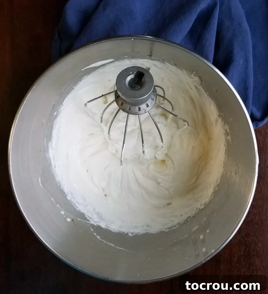 Dreamy No-Bake Pumpkin Cheesecake 4 A mixer bowl filled with rich, white cream cheese whipped cream, perfect for topping the cheesecake.