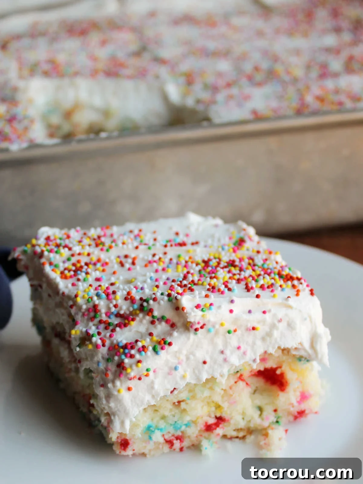 Confetti Cake with Whipped Frosting Slice of homemade confetti cake adorned with fluffy whipped condensed milk frosting and colorful sprinkles.