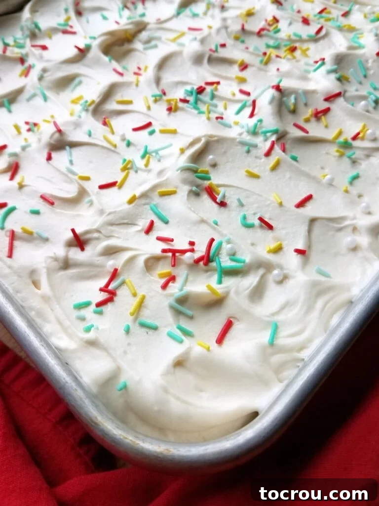 Swirled Frosting on Sheet Cake Corner of a sheet cake featuring fluffy white whipped sweetened condensed milk frosting with light swirls, topped with vibrant sprinkles.