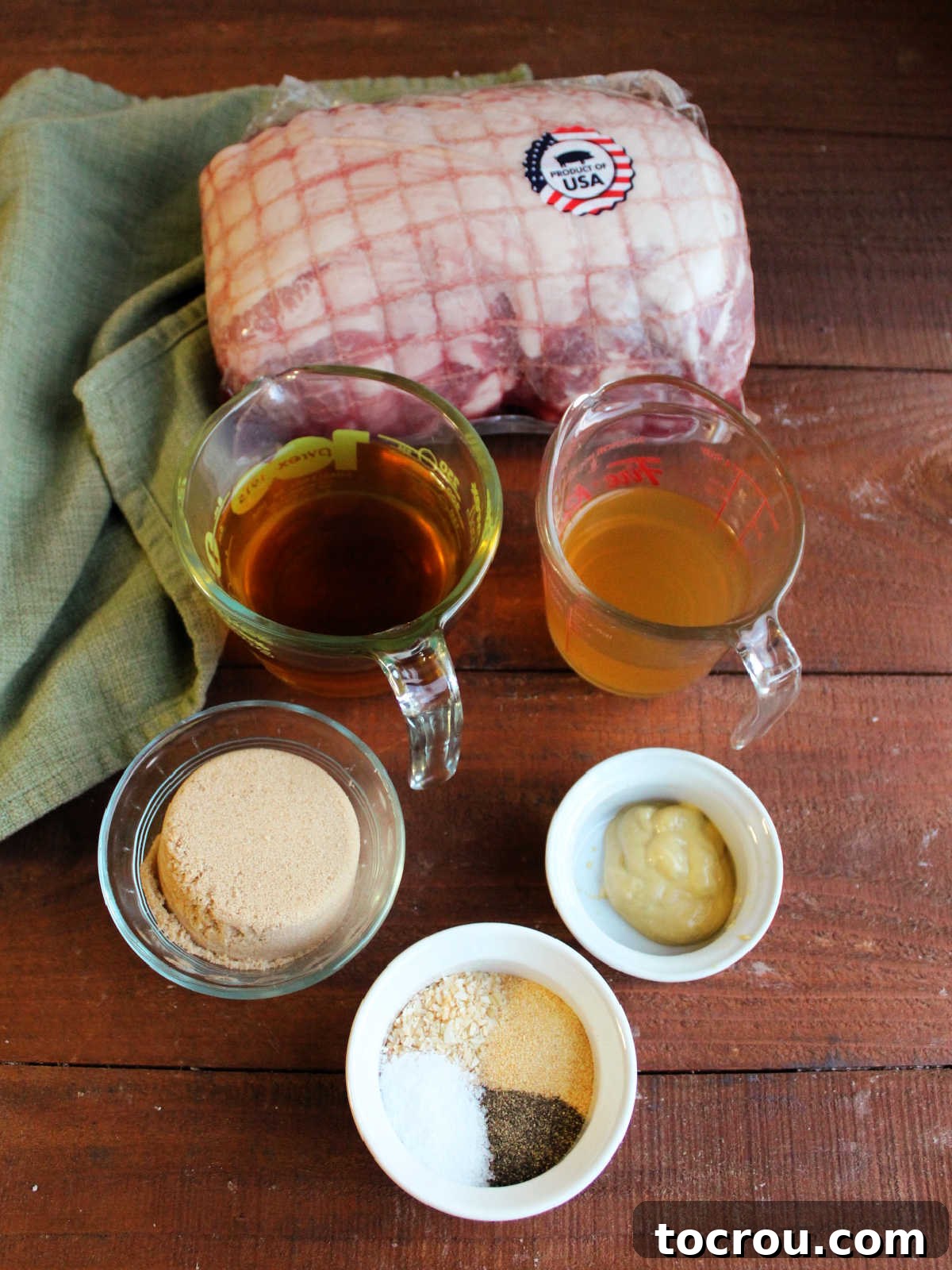 Ingredients including a large pork roast, apple cider, apple cider vinegar, mustard, brown sugar, salt, pepper, garlic, and onions meticulously arranged, ready to be prepared for braising.