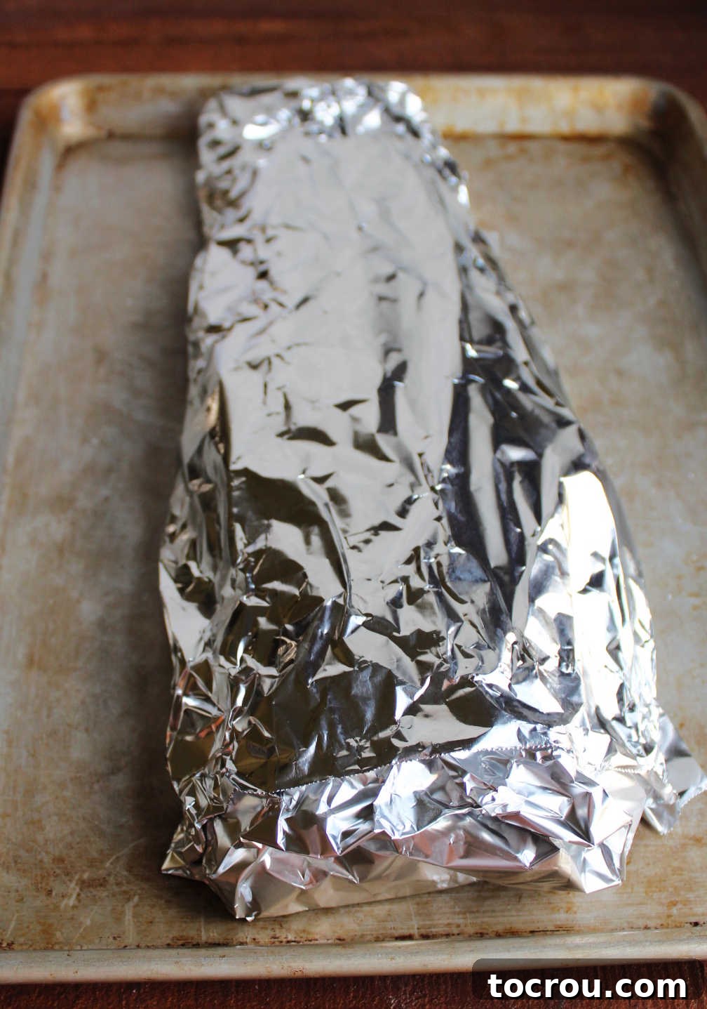 Foil-Wrapped Salmon for Baking The salmon and its seasonings neatly wrapped in aluminum foil on a baking pan, ready to be placed into the oven, ensuring tender, moist results.