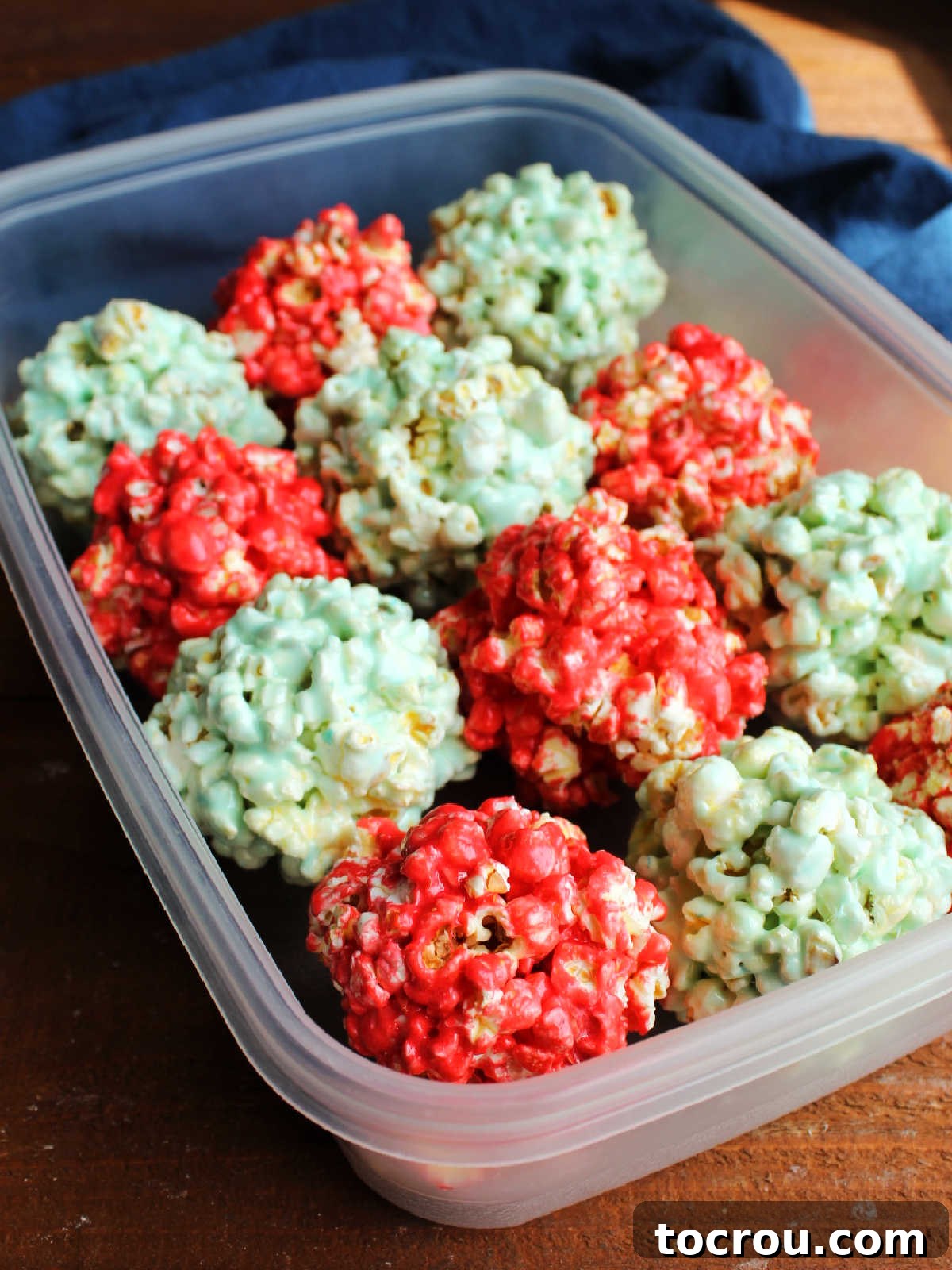 Storage container filled with red and blue marshmallow popcorn balls, ready for snacking.