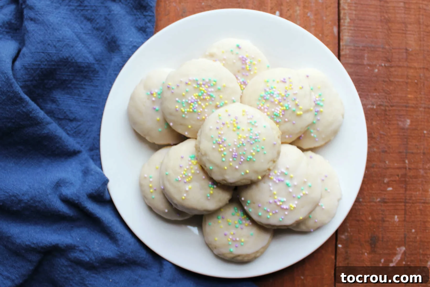 Heirloom Tea Cakes 2 A plate brimming with golden-brown grandma's white cookies, lovingly adorned with a shimmering powdered sugar glaze and festive tiny sprinkles, inviting you to take a bite.