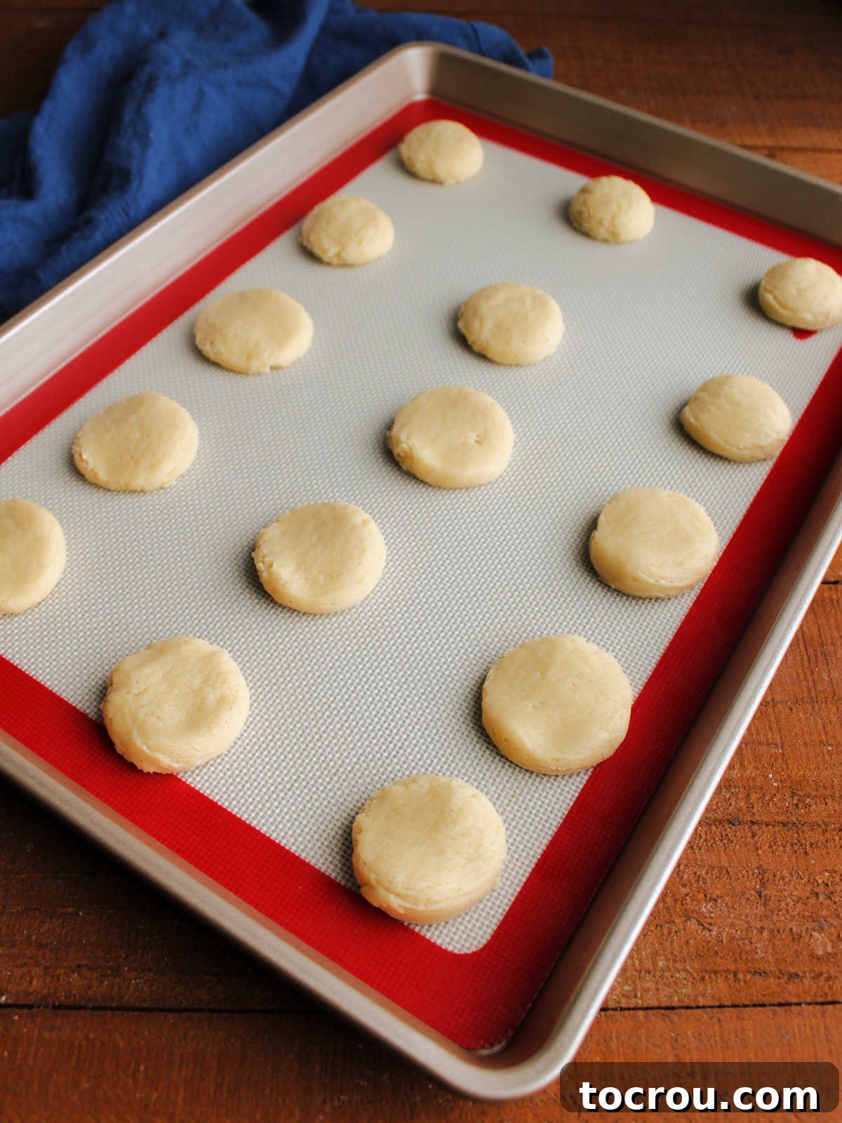 Heirloom Tea Cakes 7 Precisely scooped portions of tea cake dough, gently flattened and neatly arranged on a baking sheet lined with a silicone mat, poised and ready for their turn in the warm oven.