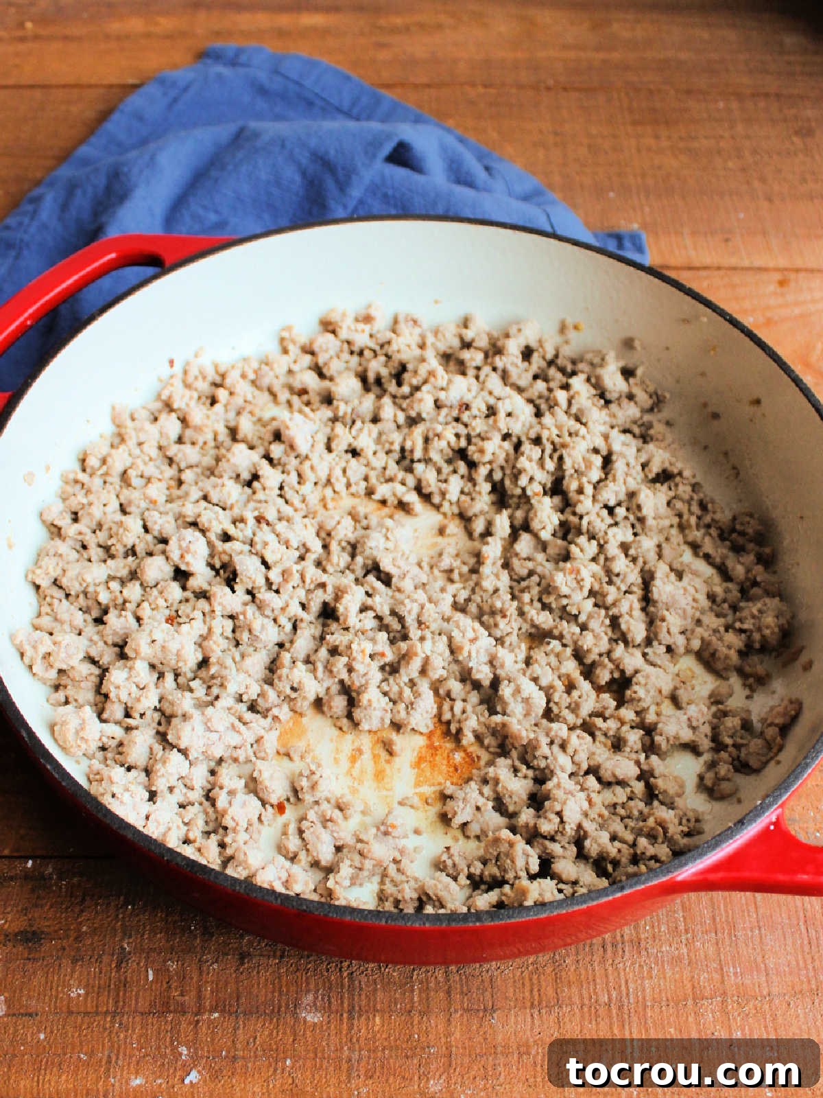 Ground pork browning in a large pan, seasoned with aromatic garlic and ginger, preparing for the rich sauce to be added.
