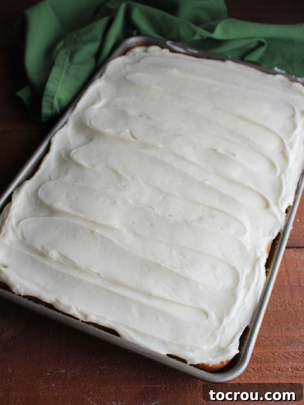 Frosted Pineapple Sheet Cake The fully baked and cooled pineapple sheet cake, magnificently topped with a thick, smooth layer of creamy white cream cheese frosting.