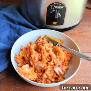 Bowl of crockpot golumpki with cooked cabbage, rice, and meat in a tomato sauce with a fork, ready to eat.