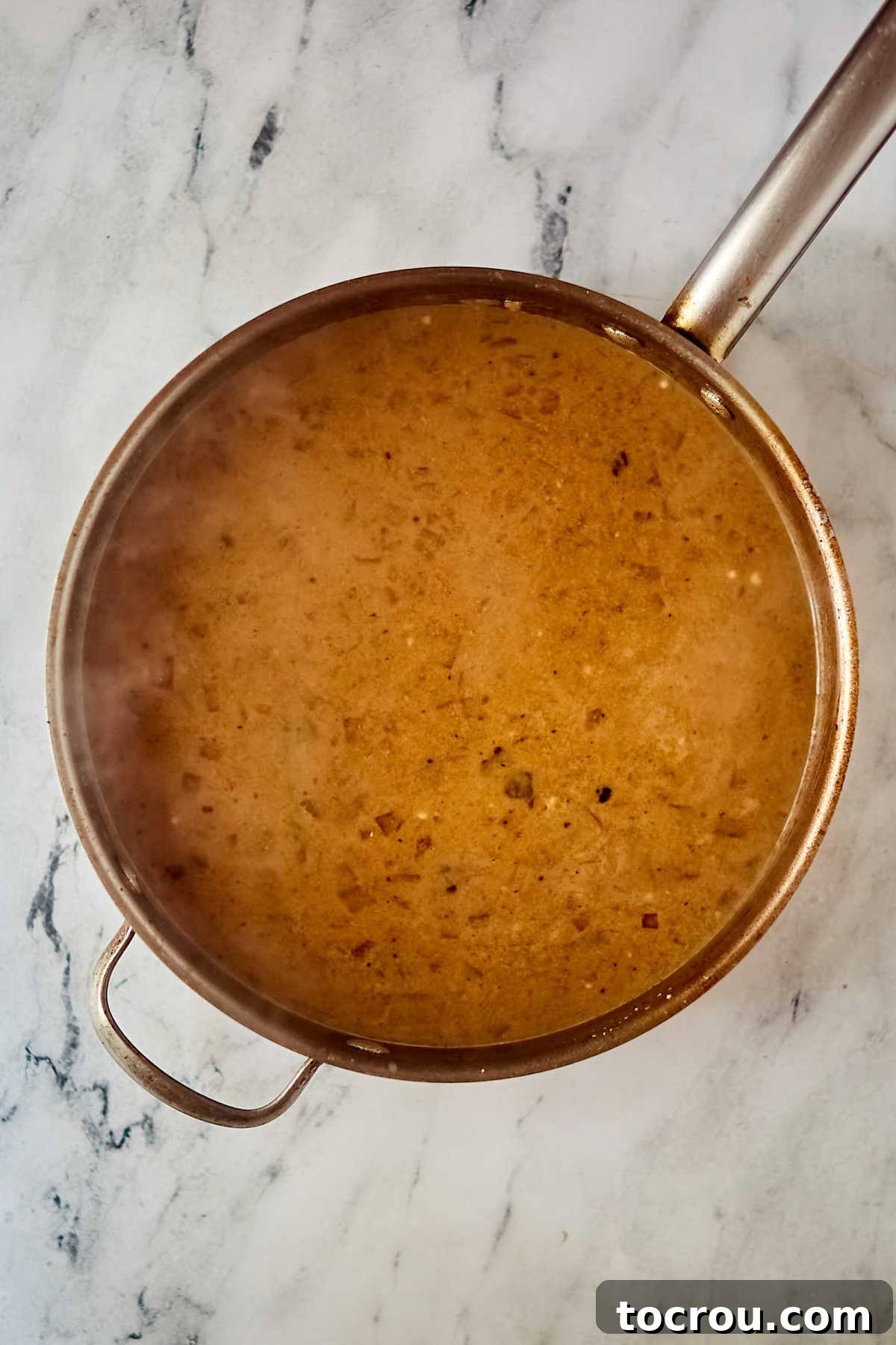 Pan of creamy gravy after the sour cream and flour mixture has been cooked into the cooking juices.