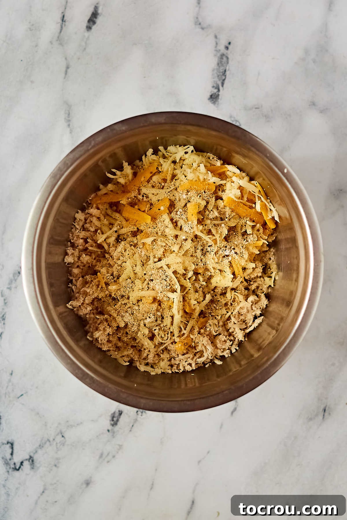 Chicken Enchilada Filling Mixing bowl filled with shredded chicken, cheese, and a blend of seasonings for the enchilada filling.