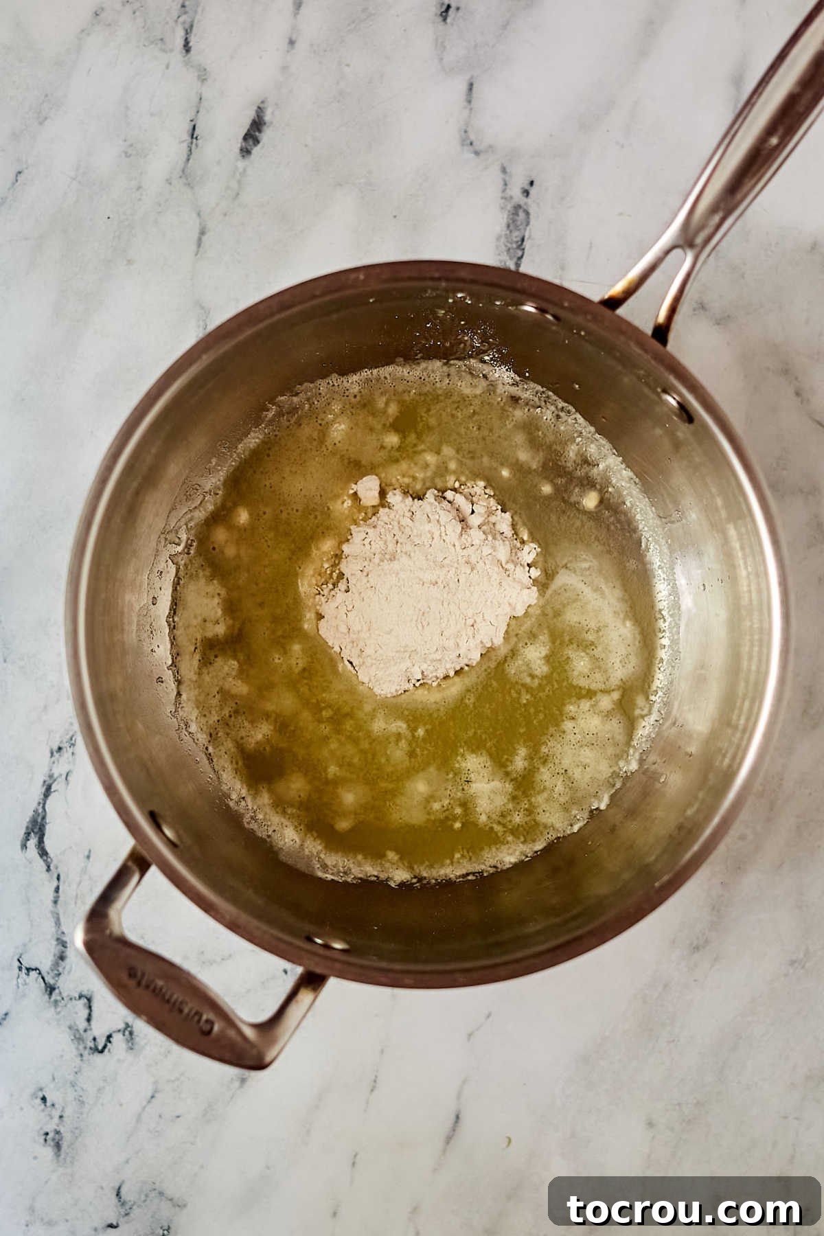 Roux for White Enchilada Sauce Melted butter and flour creating a roux in a saucepan, the first step for a creamy sauce.