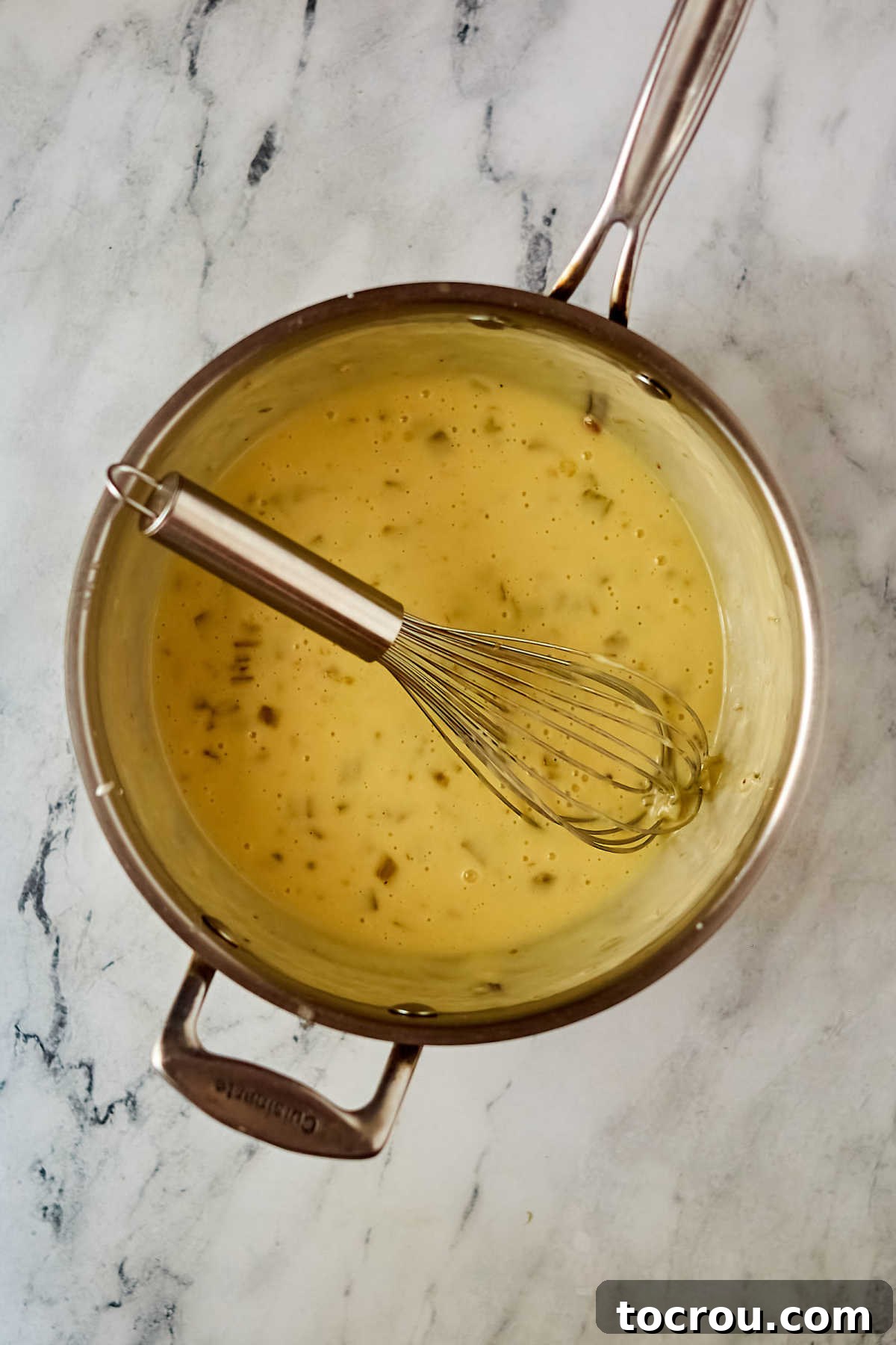 White Enchilada Sauce Prepared white enchilada sauce with melted cheese and sour cream, dotted with bits of chopped green chilies, ready to be poured over enchiladas.