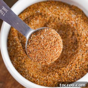 Close up of a small bowl of homemade fajita seasoning with a tablespoon getting a scoop out to use.