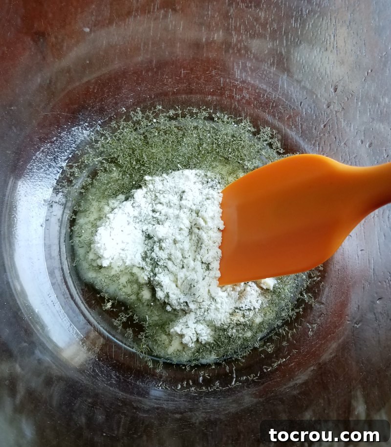 A bowl of vegetable oil mixed with ranch seasoning, dill, and garlic powder, ready for coating crackers.