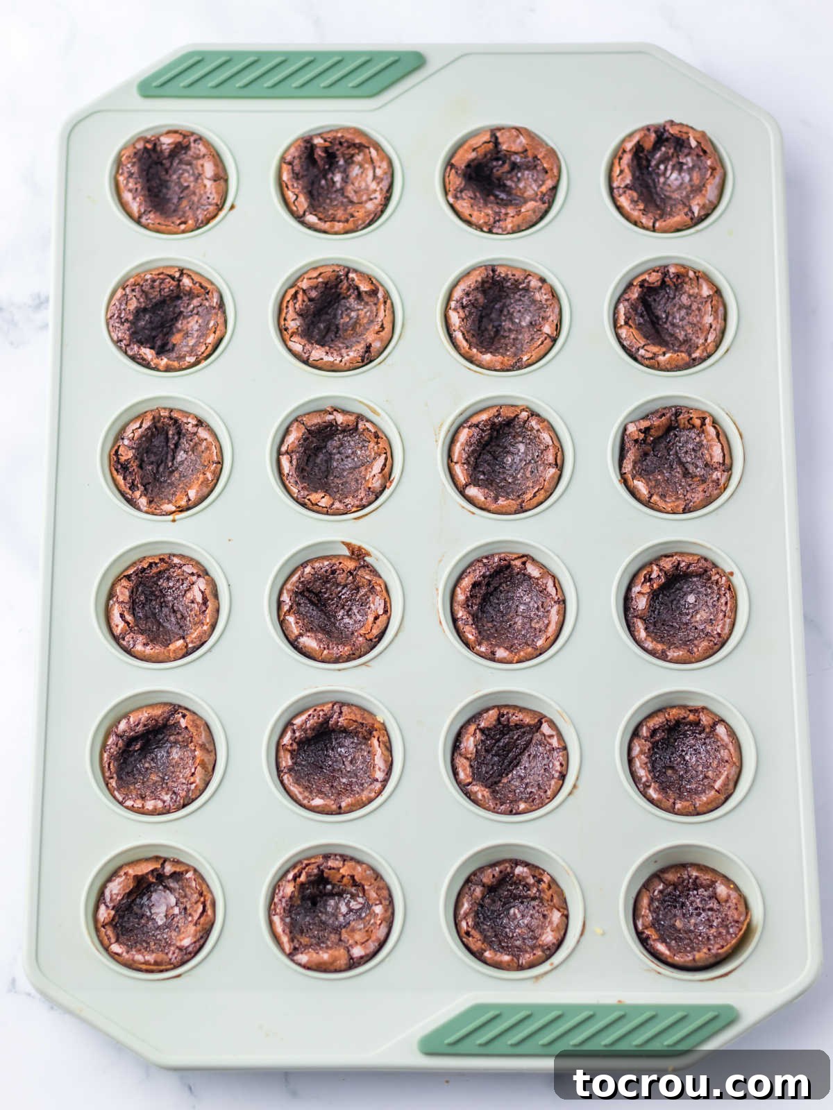 Mini Brownies Baked in Pan Brownies baked in mini cupcake pan with centers pressed down a bit to form a cup.