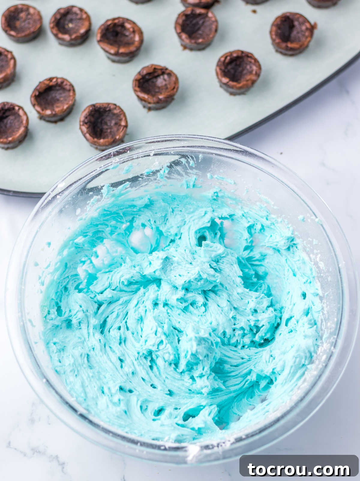Blue Buttercream and Brownies Bowl of blue buttercream with brownies in the background.