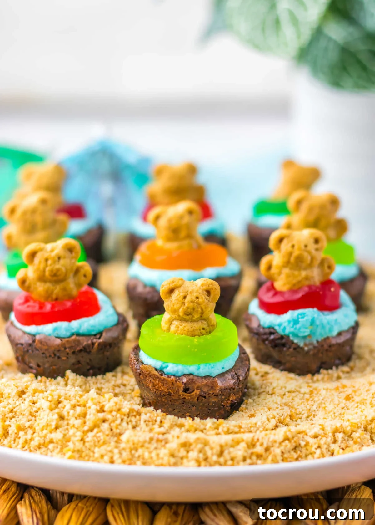 Beach Brownie Bites Platter Teddy grahams in gummy life saver floats in blue frosting water on top of brownie bites on platter with graham cracker crumb sand, ready to be served.