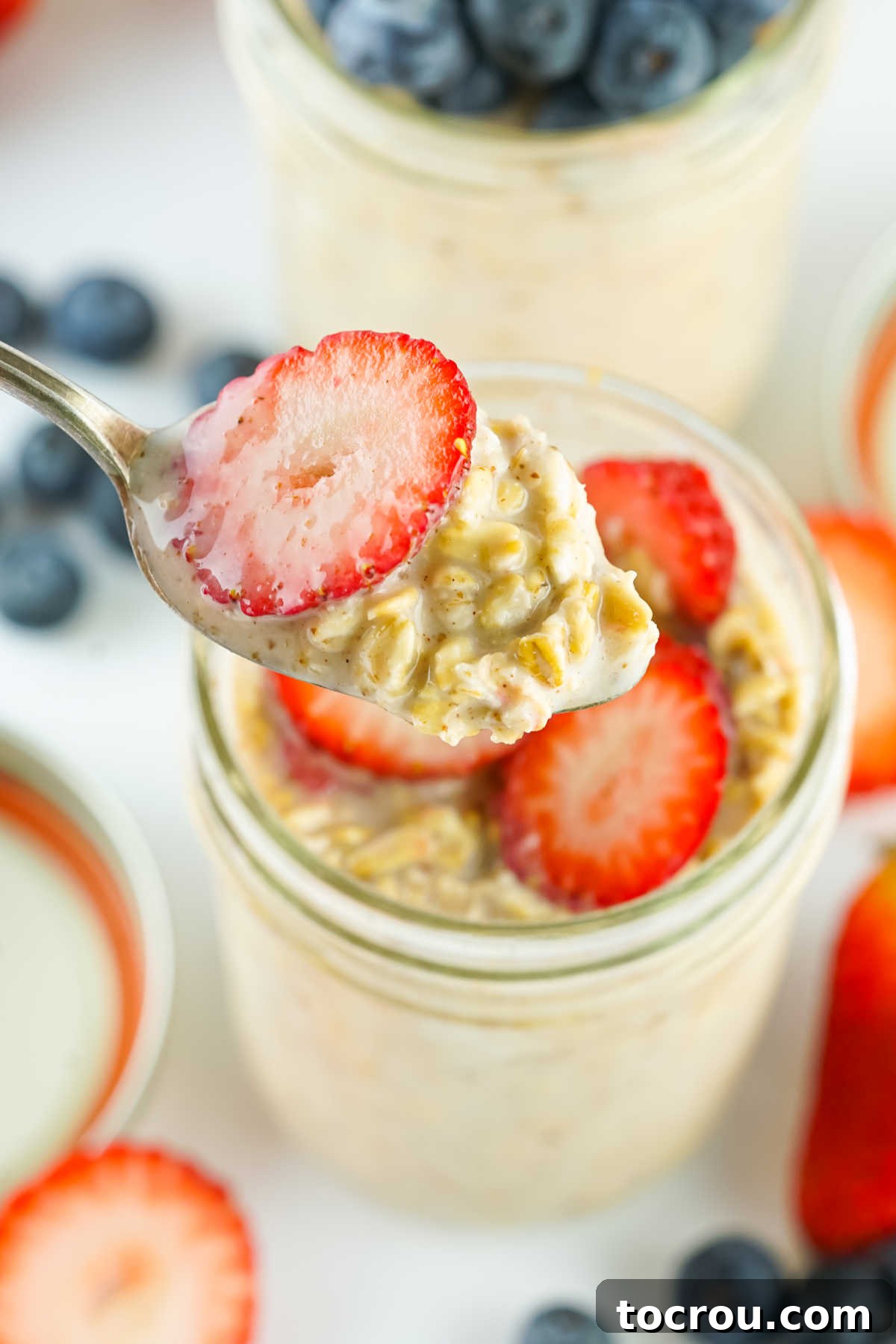 Velvety Overnight Oats 6 Spoon with a bite of creamy overnight oats topped with a fresh strawberry slice.