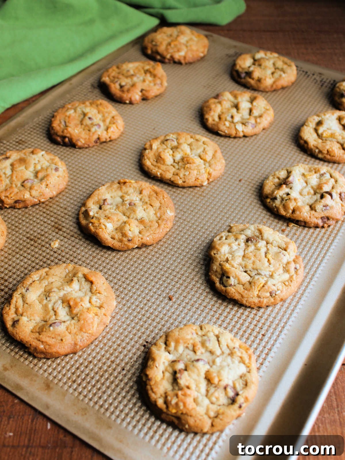 Baked cornflake cookies on cookie sheet showing golden color and rippled texture. 