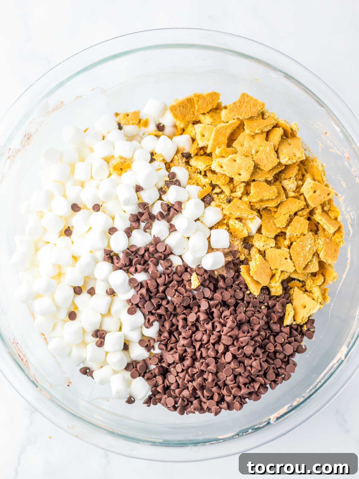 Smores Cloud 5 Adding bits of graham crackers, mini chocolate chips, and mini marshmallows to mixing bowl with pudding mixture.