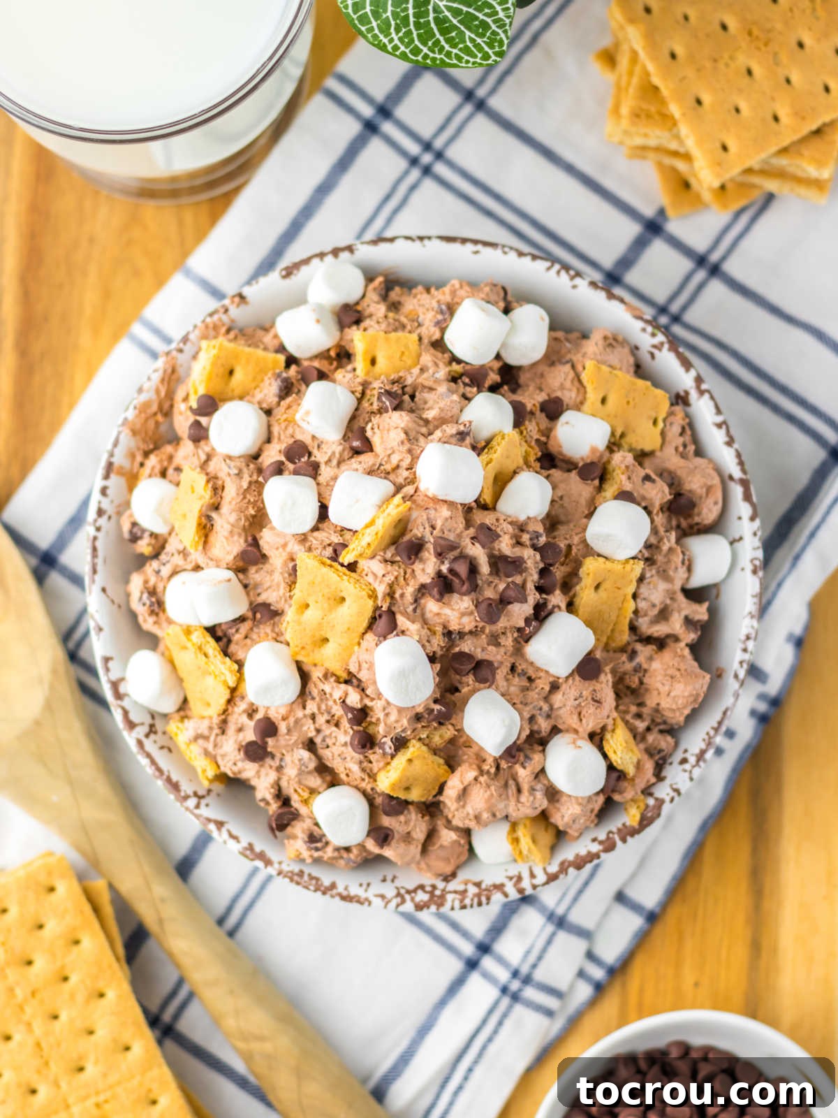 Smores Cloud 8 Serving bowl piled with chocolate s'mores fluff topped with bits of graham crackers, mini chocolate chips, and mini marshmallows.