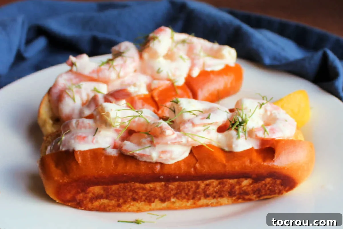 Close up of toasted brioche bun piled high with shrimp in mayo, brown butter, and lemon dressing topped with chopped fresh dill. 