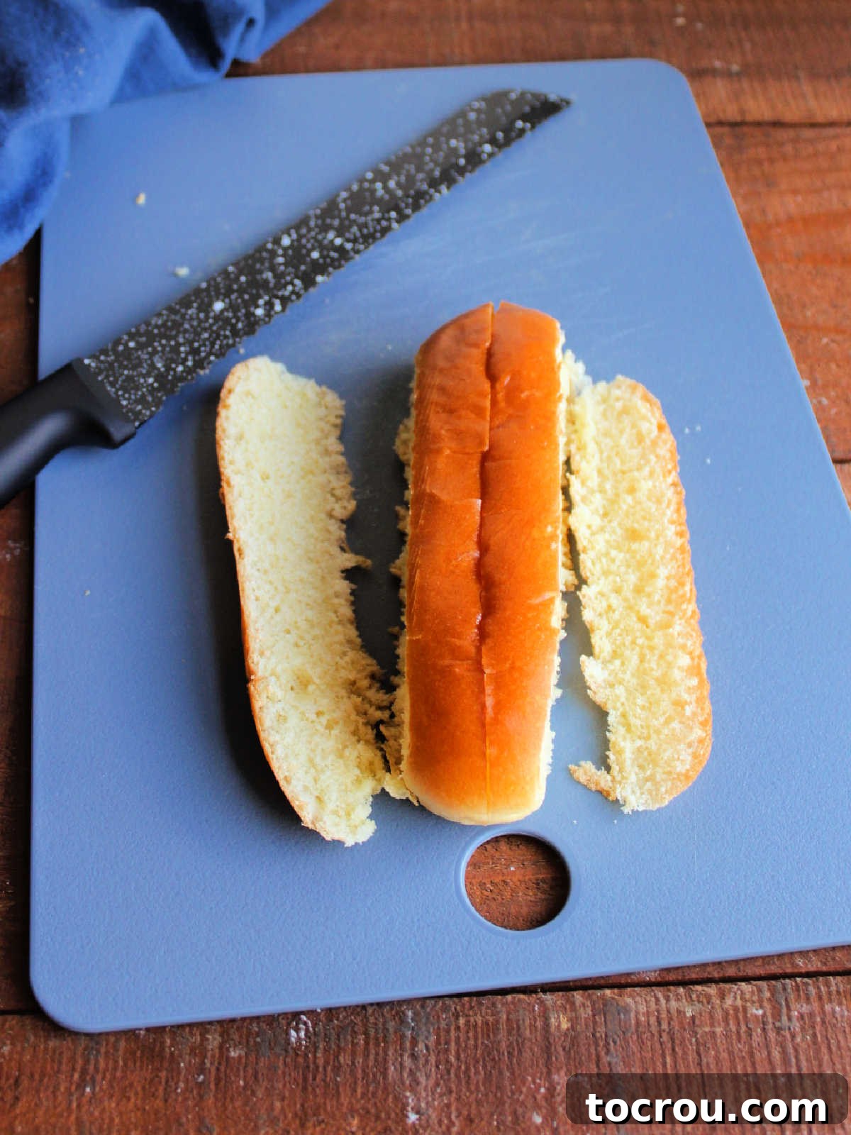 Trimming the edges off a split top hot dog bun to give a flat spot to butter and toast. 