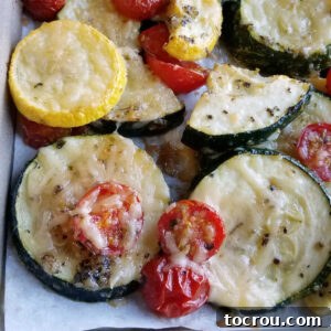 Parmesan roasted zucchini and cherry tomatoes fresh from the oven with melted cheese and seasonings on the cooked veggies.