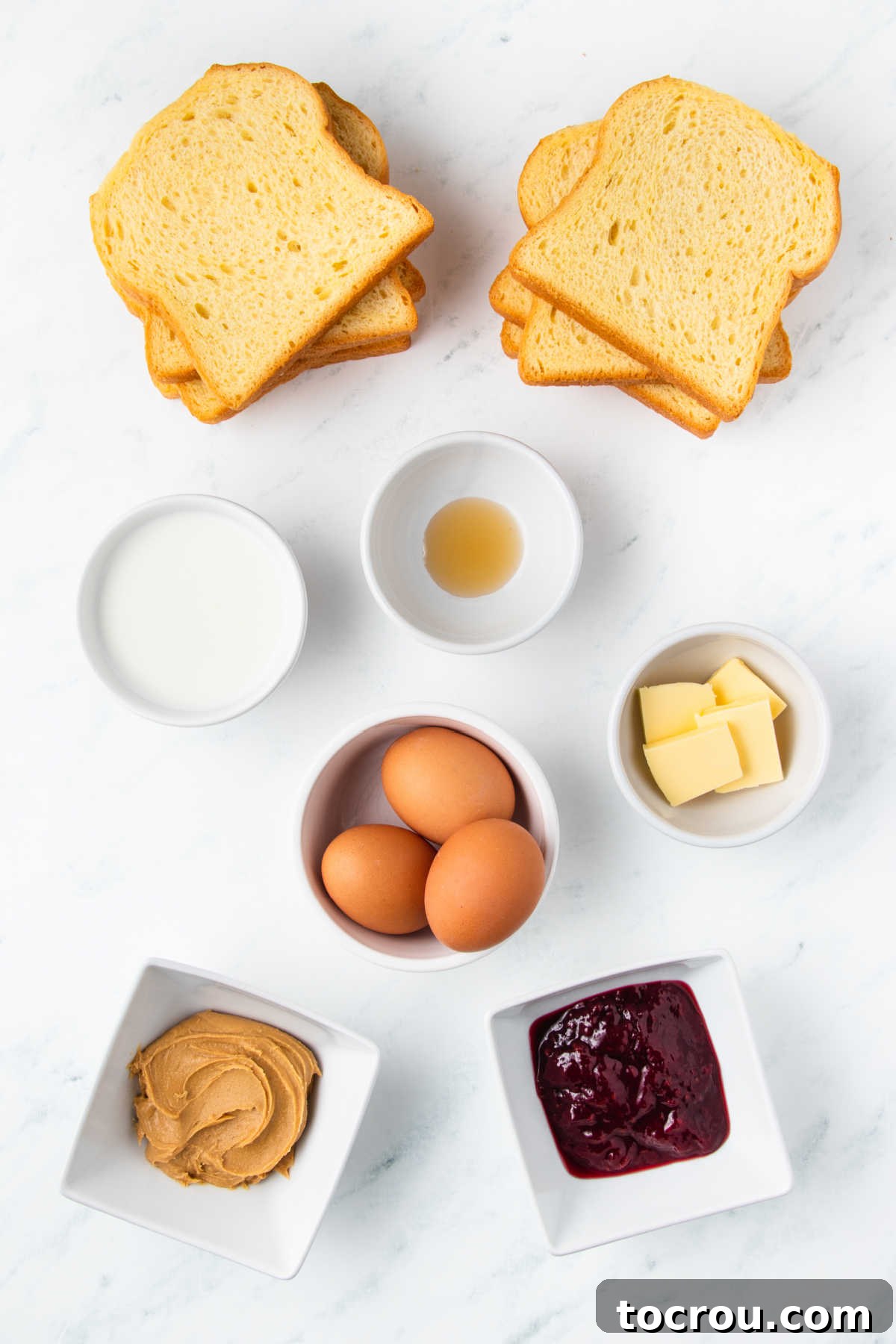 Peanut Butter and Jelly Stuffed French Toast 3 Ingredients including slices of bread, peanut butter, jam, eggs, milk, vanilla, and butter ready to be made into pbj french toast.