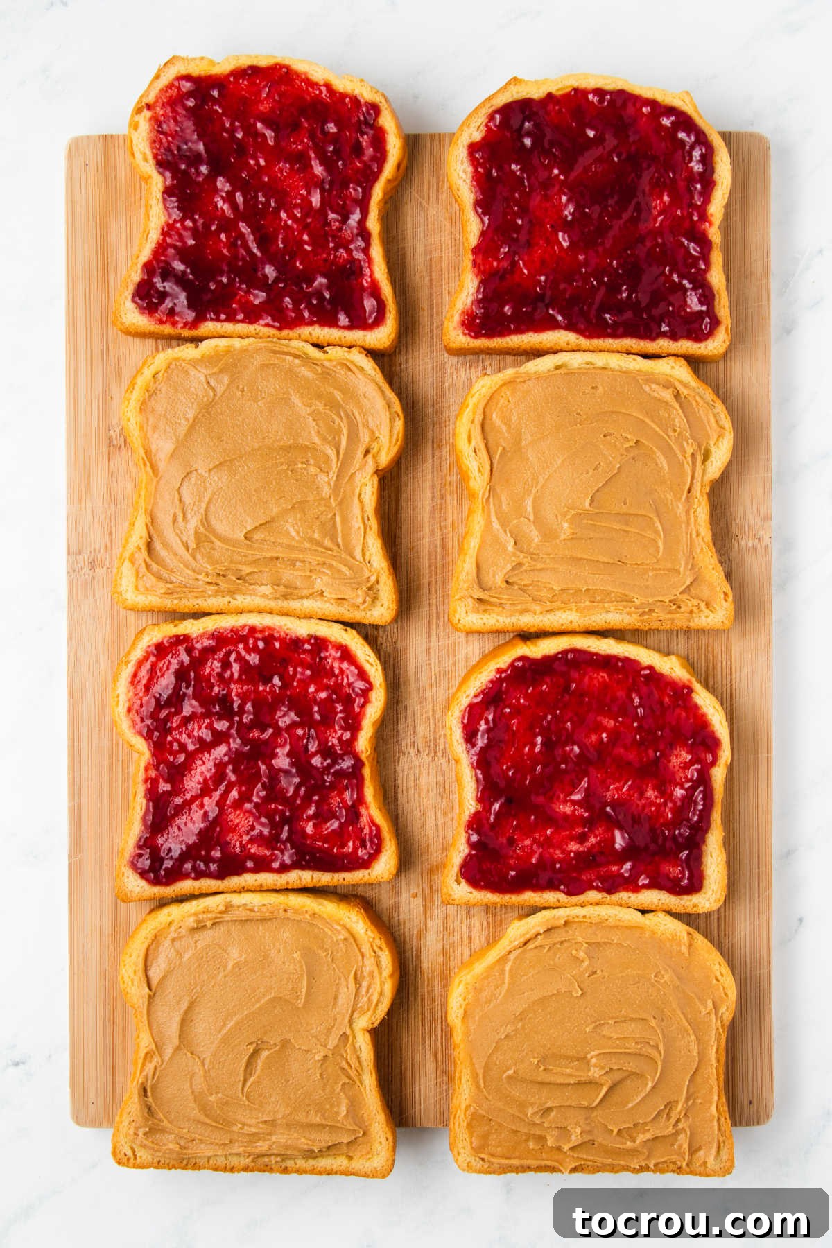 Peanut Butter and Jelly Stuffed French Toast 4 8 slices of bread, half with peanut butter spread over them and the other half with raspberry preserves on them.