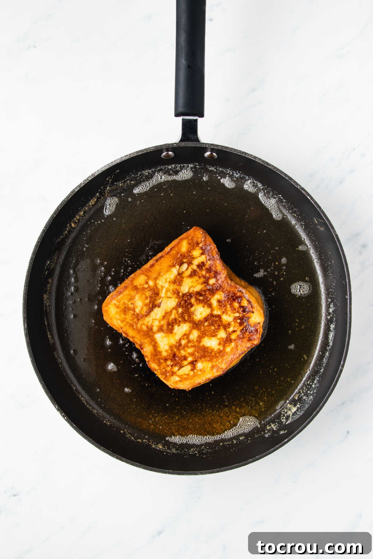 Peanut Butter and Jelly Stuffed French Toast 6 Skillet with melted butter and french toast inside showing golden brown finish on the custard soaked bread after it is done cooking.